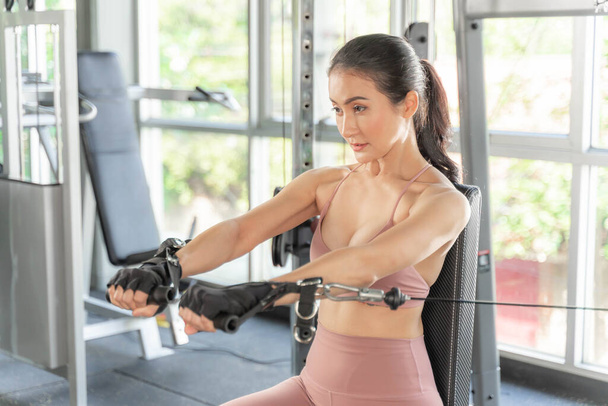 Mooie fitness slanke fitnessvrouw in sportkleding werkend met een Cable Crossover apparaat in een fitnessruimte, Aziatisch sexy meisje slank lichaam - fitness model concept. - Foto, afbeelding