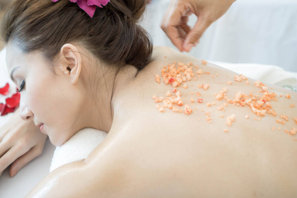 красивая и здоровая женщина, наслаждающаяся солевым массажем спины в спа-салоне - Фото, изображение