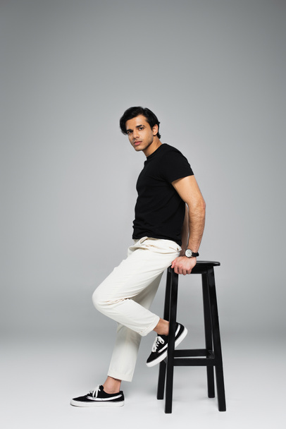 full length of young man sitting on chair on grey - Foto, immagini