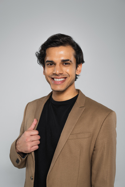 cheerful young man in stylish blazer posing isolated on grey  - Foto, Imagen