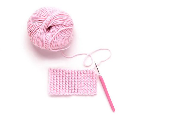 白い背景にピンクの編み物糸と編み物のかぎ針編みのボール。フラットレイアウト、トップビュー。手作り - 写真・画像