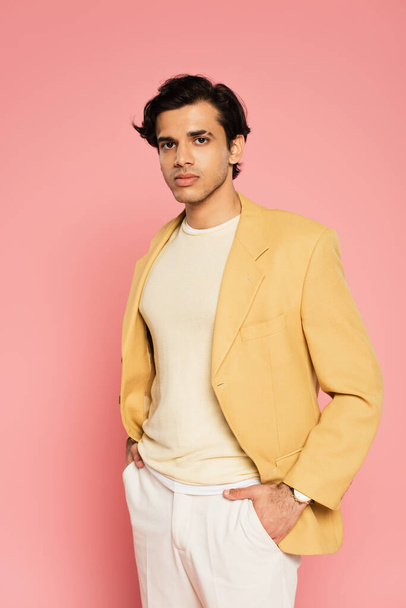 young man in yellow blazer posing with hands in pockets on pink  - Photo, Image