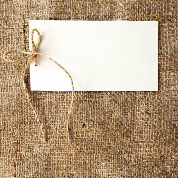 Vintage style congratulation or invitation white card on rustic burlap backgroun - Foto, afbeelding