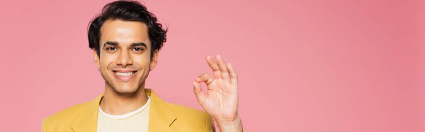 happy young man in yellow blazer showing ok sign isolated on pink, banner - Foto, Bild