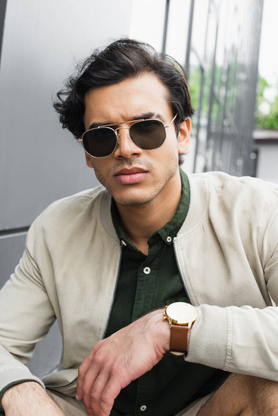 man in stylish sunglasses and bomber jacket looking at camera - Photo, image