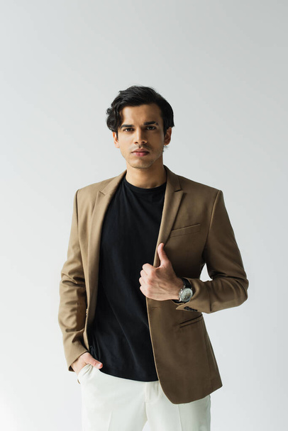 young man in stylish beige blazer looking at camera isolated on grey - Foto, immagini