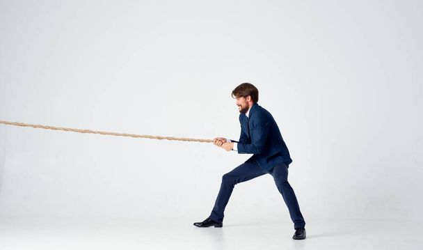 hombre de negocios en un traje tira de la cuerda estudio luz fondo - Foto, Imagen