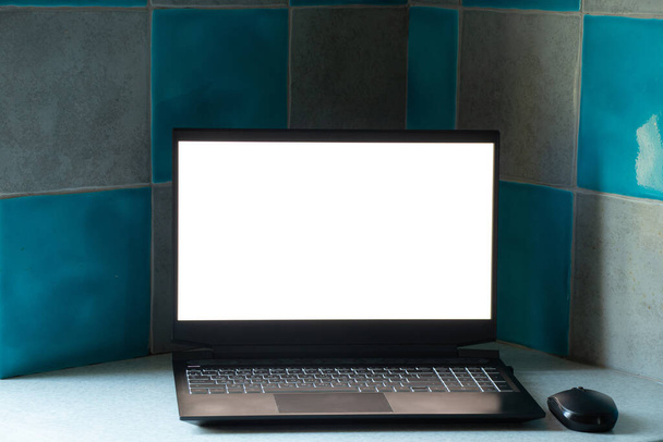 白い画面の黒いノートパソコンは自宅のテーブルのキッチンに、白い画面のノートパソコンは、テーブルの上にテンプレート、ノートパソコンは - 写真・画像