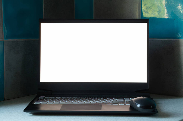 czarny laptop z białym ekranem stoi w kuchni na stole w domu, laptop z białym ekranem, szablon, laptop na stole - Zdjęcie, obraz