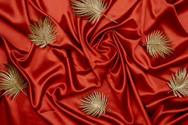 Decorative golden leaves on red textile backdrop - Fotoğraf, Görsel