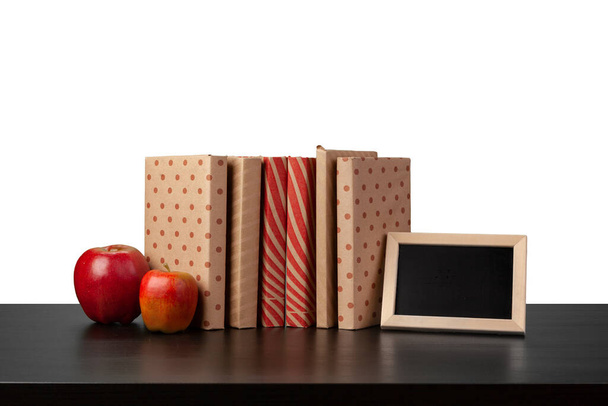 Stack of books and apple on tabletop against white background - Фото, зображення