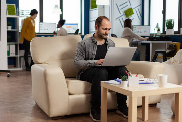 Businessman strart up modern office typing on laptop sitting on couch - Foto, Bild