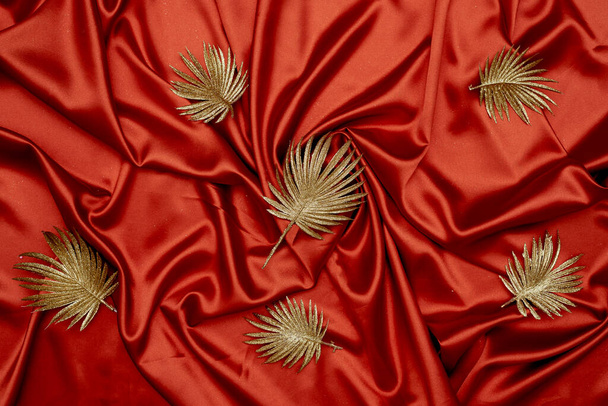 Decorative golden leaves on red textile backdrop - Fotoğraf, Görsel