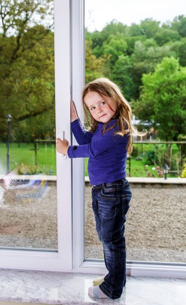 Cute little girl and pvc window - Photo, image