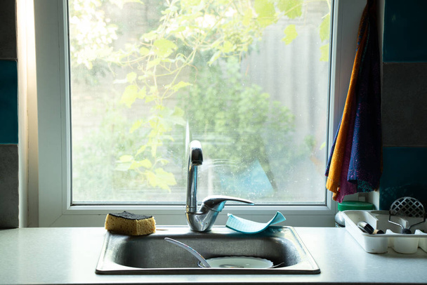 kitchen countertop with a set of clean washed dishes brought windows and sinks, kitchen table, clean plate on the shelf - Photo, image