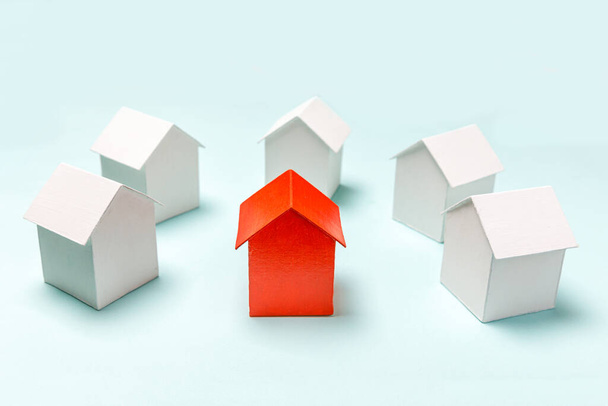 Egyszerűen design miniatűr piros játék modell ház között fehér házak elszigetelt pasztell kék háttér. Ingatlanpiac. Közösségi egyedi szomszédsági választási koncepció - Fotó, kép