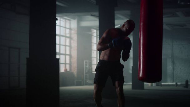 格闘クラブでボクシングの練習をしてる男。パンチングバッグで戦うボクサー - 写真・画像