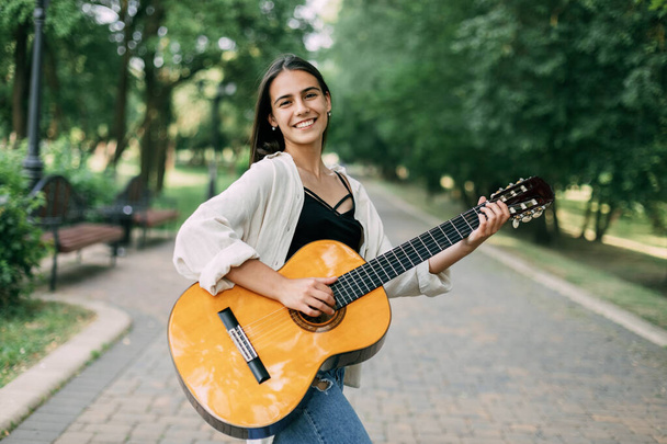 Una chica músico toca la guitarra en el parque. Música, músico, guitarra, libertad - Foto, imagen