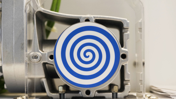 Rotierende blaue Spirale auf weißem Hintergrund. HDR. Nahaufnahme des automatisierten Mechanismus mit rotierender hypnotischer Spirale, Konzept der Hypnose und Psychotherapie. - Foto, Bild