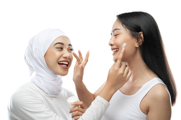 excited asian bestfriend applying face cream with finger hands - Foto, afbeelding