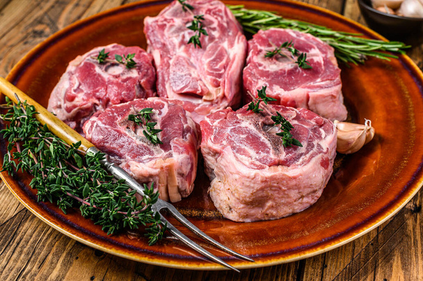 Мясо баранины на шее на деревенской тарелке с тимьяном и розмарином. деревянный фон. Вид сверху - Фото, изображение