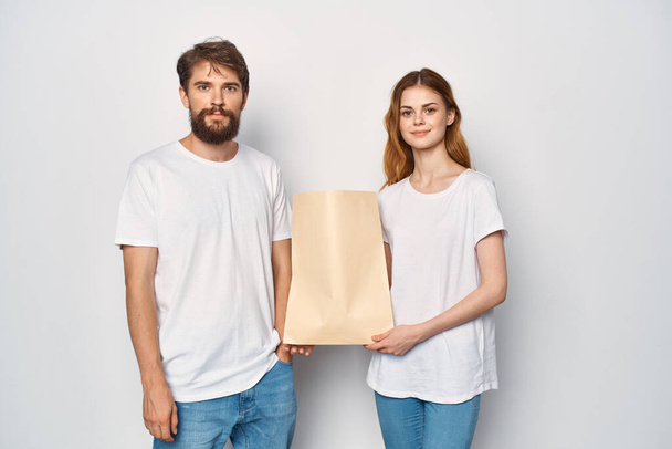 man and woman in white t-shirts paper bag shopping - Foto, imagen