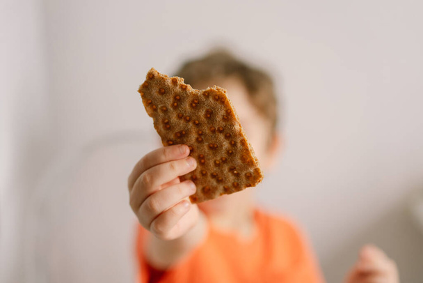 Aranyos kisfiú ropogós kenyeret eszik. Egészséges életmód és táplálkozás koncepció. - Fotó, kép