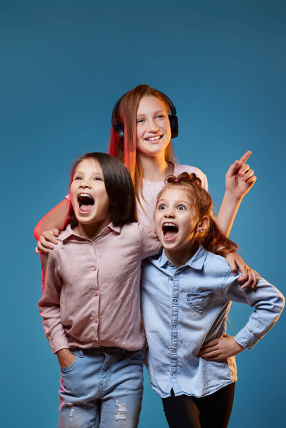 three kids girls standing together on blue background - Photo, Image