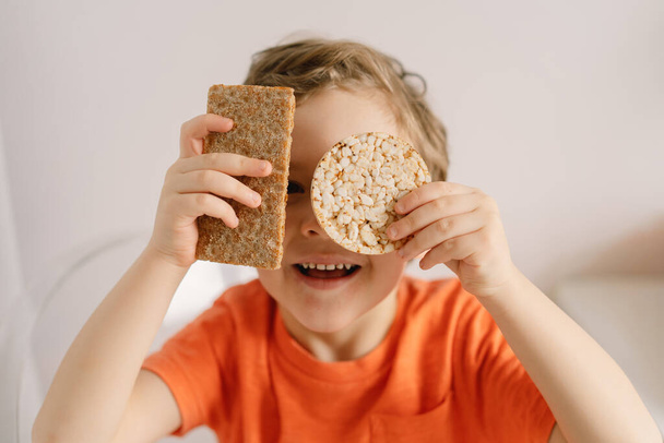 Mignon petit garçon mange du pain croustillant. Mode de vie sain et concept de nutrition. - Photo, image