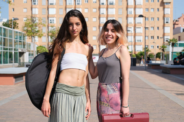 Dos mujeres posando y llevando intrumentos musicales en la calle. - Foto, imagen