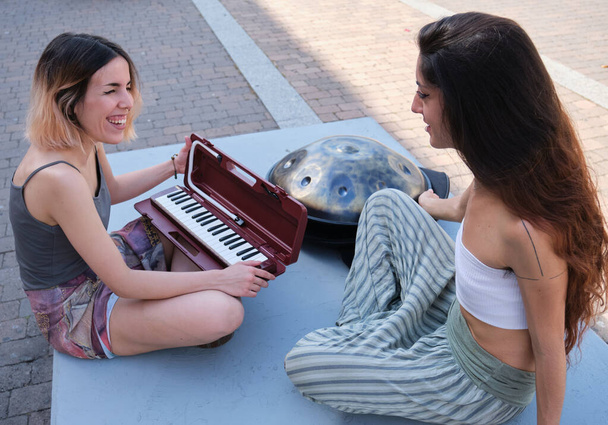 Due donne ridono e parlano mentre si preparano a suonare intrusioni musicali. - Foto, immagini