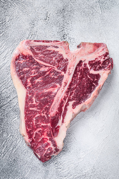 Rauwe T-bone of Porterhouse Steak op keukentafel. Witte achtergrond. Bovenaanzicht - Foto, afbeelding