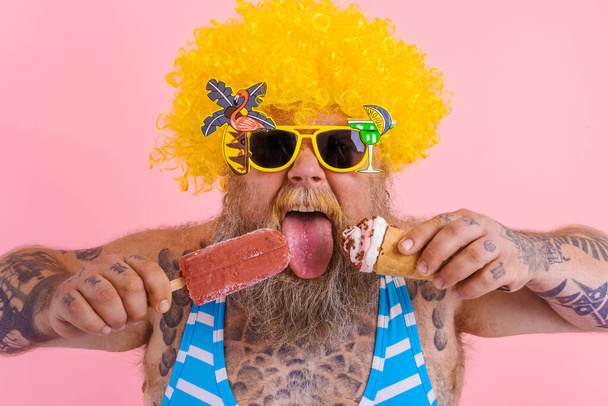 Sakallı ve peruklu şişman adam dondurma ve dondurma yiyor. - Fotoğraf, Görsel