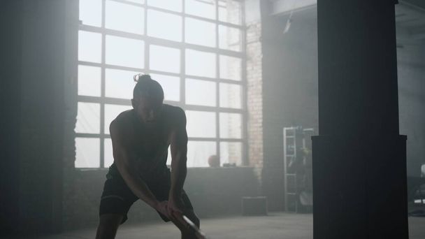 Спортсмен с помощью молотка во время тренировки. Фитнесмен бьет резиновую шину  - Фото, изображение