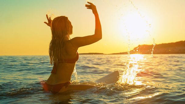 Серфінг піднімає руки вгору, дивлячись на захід сонця. - Фото, зображення