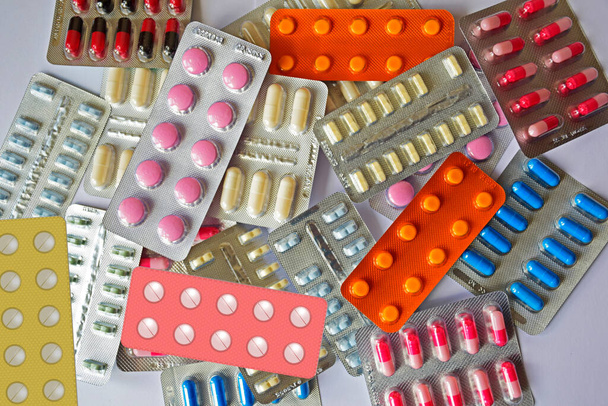 Colorful tablets and capsule pills in blister pack. Close-up on a light background. Full colored pills package. Pharmaceutical blister pack. Pack of pills with tablets. - Photo, Image