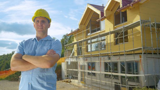 CLOSE UP: Smiling contractor proudly stands in front of house under construction - Photo, Image