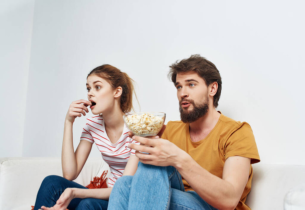 молода подружня пара розслабляється вдома на дивані попкорн розваги
 - Фото, зображення