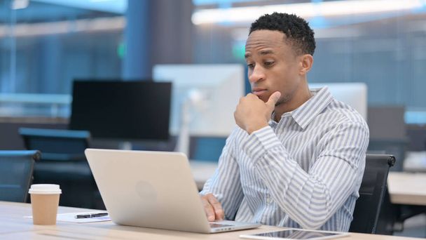 Young African Businessman with Laptop Thinking at Work - Photo, Image