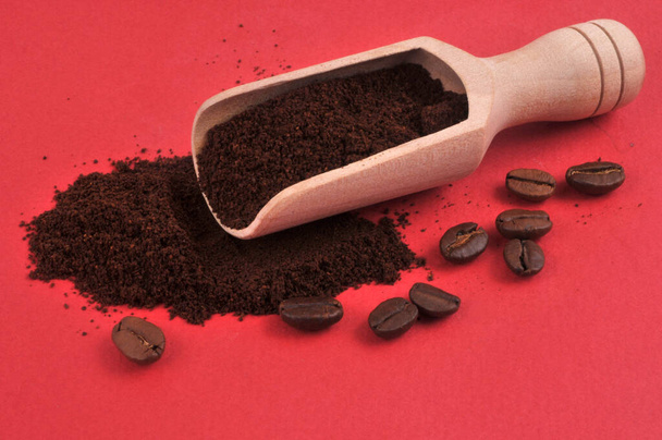 Granos de café y cuchara de madera de café molido de cerca sobre fondo rojo  - Foto, imagen