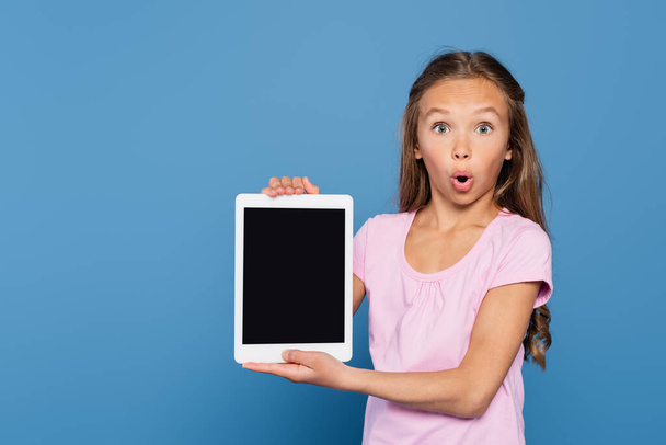 驚きの子供は青い上に隔離された空白の画面を持つデジタルタブレットを保持  - 写真・画像