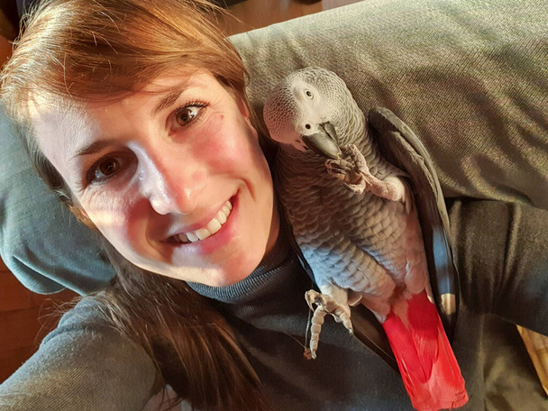 SELFIE: Cute shot of a friendly parrot lying on its cheerful owner's shoulder. - Photo, Image