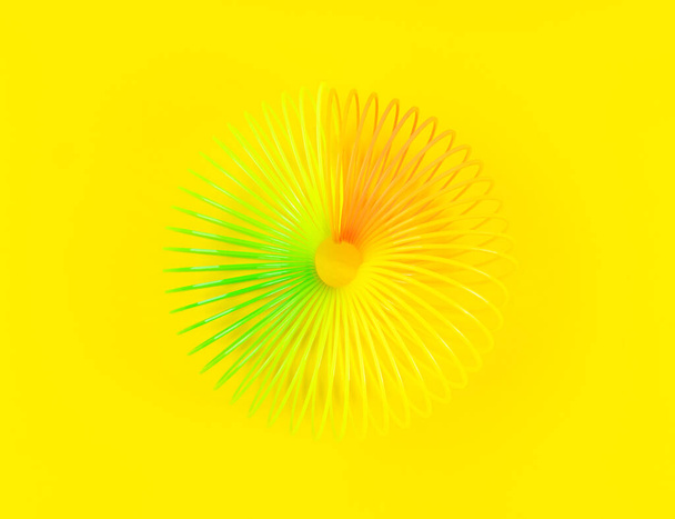 Sarı arkaplanda renkli spiral plastik oyuncak - Fotoğraf, Görsel