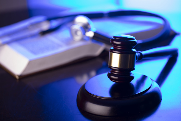 Medical law concept. Gavel, legal code and stethoscope on the glass table. Blue light. - Photo, Image