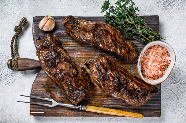 Grilled brisket steaks in bbq sauce on a wooden board. White background. Top view - Photo, Image