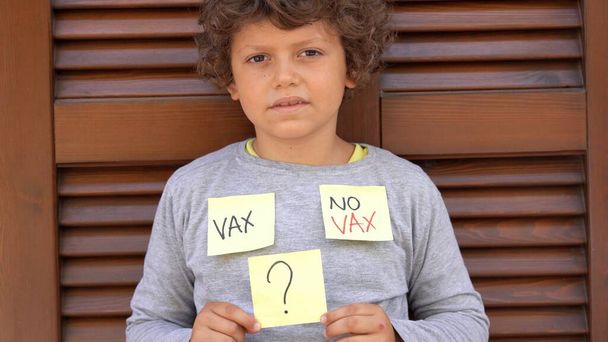 Europa, Itália, decisão de vacinar ou não vacinar (sem vax) crianças pequenas. Criança de 7 anos de idade indecisa sobre a vacinação contra o Covid-19 Coronavirus - Foto, Imagem
