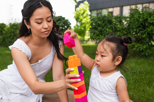 asian toddler girl and young mother playing building blocks in park  - Photo, Image