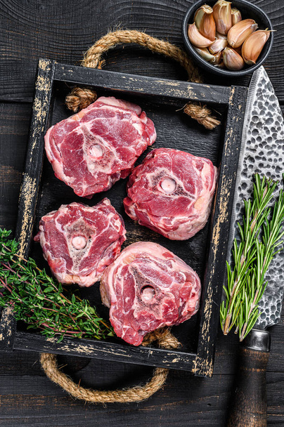 Сырое мясо из баранины на столе мясника с ножом. Черный деревянный фон. Вид сверху - Фото, изображение