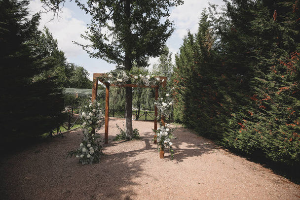 Rustic wedding arch for an ceremony decorated with white and flowers. - Foto, Imagen