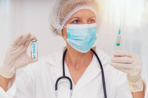 Лікар з маскою і шприцом готовий вводити вакцину проти ковадла 19
 - Фото, зображення